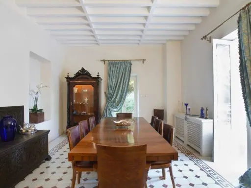 Elegancki salon w stylu kolonialnym z drewnianym stołem, witryną i zdobioną skrzynią.