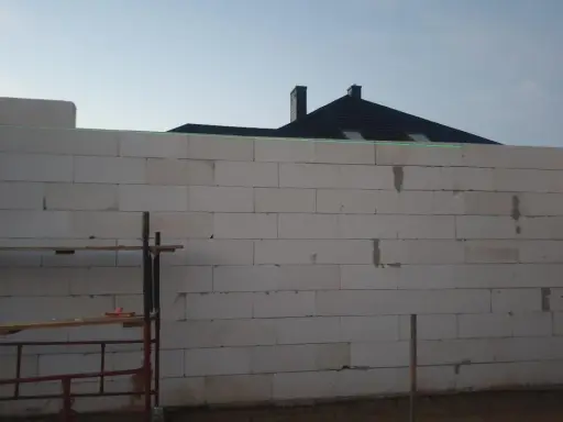 Budowa domu z bloczków, zielona linia laserowa wyznacza poziom. To dobry pomysł na krzywe ściany, jeśli chcesz uzyskać ciekawy efekt architektoniczny.