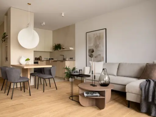 Nowoczesna jadalnia inspiracje: minimalistyczny stół z szarymi krzesłami, obok kuchnia i salon z beżową kanapą.