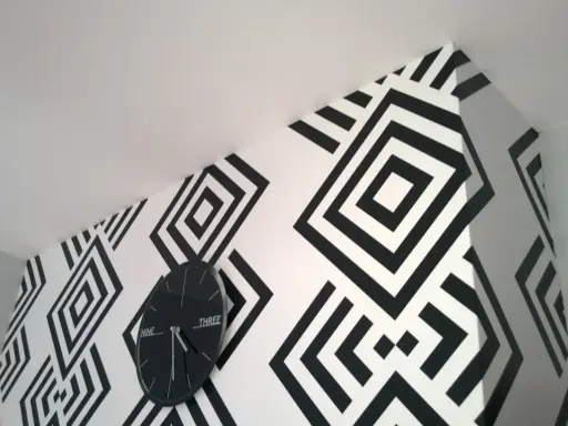 Nowoczesne tapety biało czarne z geometrycznym wzorem rombów. Zegar ścienny w czarnej ramie idealnie komponuje się z aranżacją.