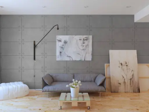 Nowoczesne wnętrze z panelami imitującymi beton. Sofa, stolik z palety, biały puf i obrazy tworzą stylową aranżację.