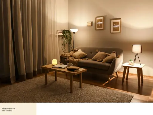 Przytulny salon z kanapą, stolikiem i dywanem. Dominują **ciepłe odcienie dębu**, tworząc relaksującą atmosferę.