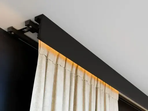 Nowoczesna szyna sufitowa z ukrytym oświetleniem LED, na której wiszą beżowe zasłony. Eleganckie rozwiązanie zamiast tradycyjnego karnisza.
