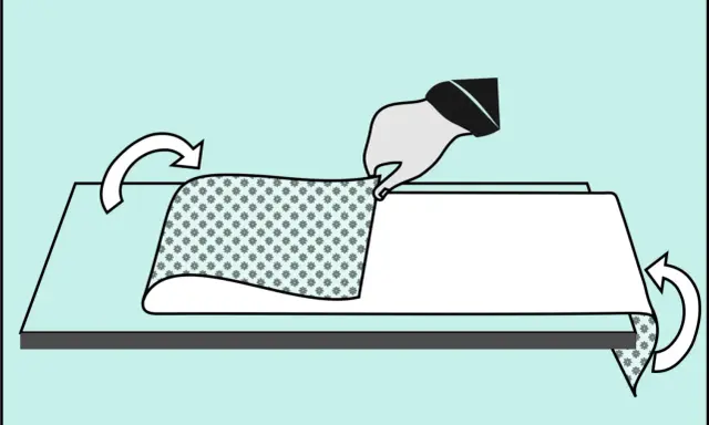 Ręka trzyma tapetę z wzorem kwiatowym, przygotowując ją do tapetowania przy otworach okiennych i drzwiowych. Strzałki wskazują kierunek składania.