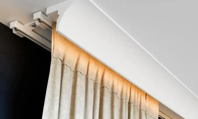 Nowoczesna blenda przy suficie ukrywa szynę zasłonową, tworząc elegancką linię.