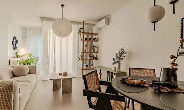 Salon w stylu japandi z beżową sofą, kamiennym stolikiem i drewnianymi meblami.