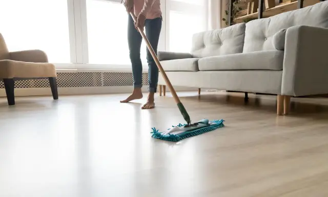 Osoba myje podłogę mopem, zastanawiając się, czym myć panele plastikowe.
