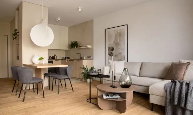 Nowoczesna jadalnia inspiracje: minimalistyczny stół z szarymi krzesłami, obok kuchnia i salon z beżową kanapą.