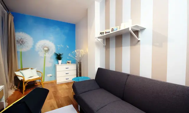 Jasne, oto propozycja:

Salon z fototapetą z dmuchawcami i asymetryczne pasy na ścianie tworzą przytulną atmosferę.