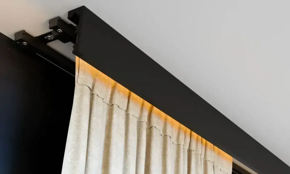 Nowoczesna szyna sufitowa z ukrytym oświetleniem LED, na której wiszą beżowe zasłony. Eleganckie rozwiązanie zamiast tradycyjnego karnisza.