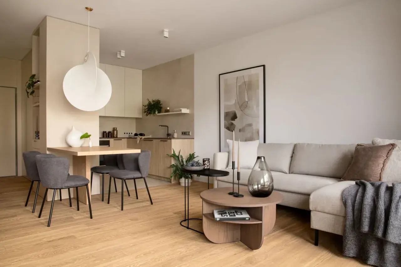 Nowoczesna jadalnia inspiracje: minimalistyczny stół z szarymi krzesłami, obok kuchnia i salon z beżową kanapą.