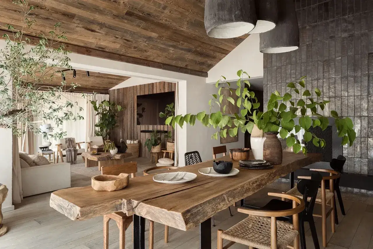 Drewniane wnętrze z roślinnością, stołem z litego drewna i elementami biophilic design.