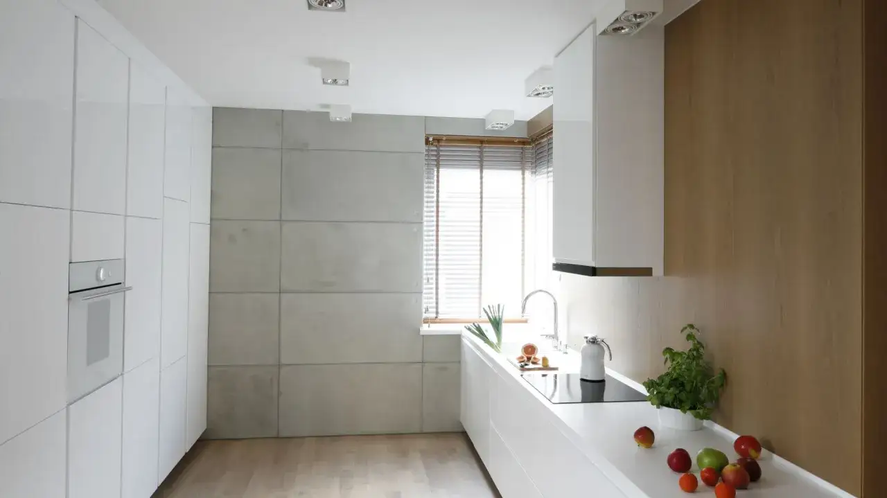 Nowoczesna kuchnia z białymi frontami i betonem architektonicznym na ścianie. Inspiracje dla miłośnik&oacute;w surowego stylu.