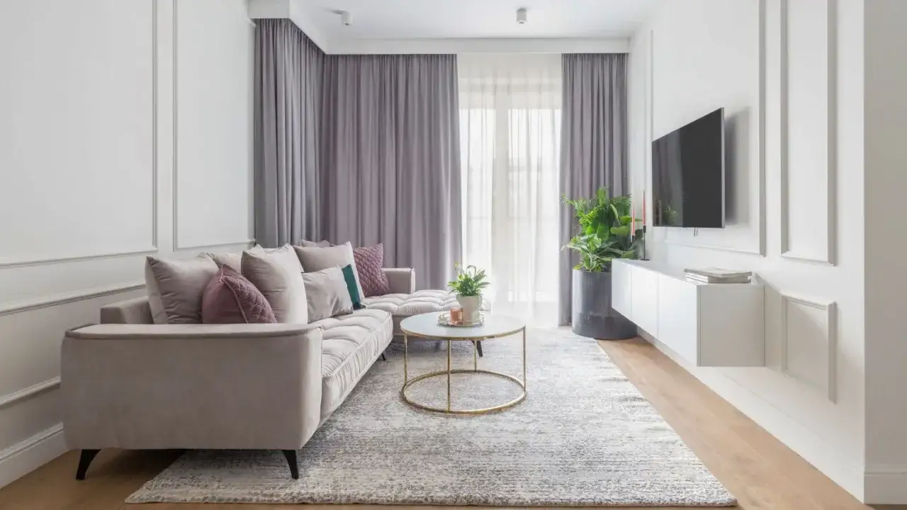 Elegancki, modern classic salon z wygodną sofą, okrągłym stolikiem kawowym i telewizorem na ścianie.