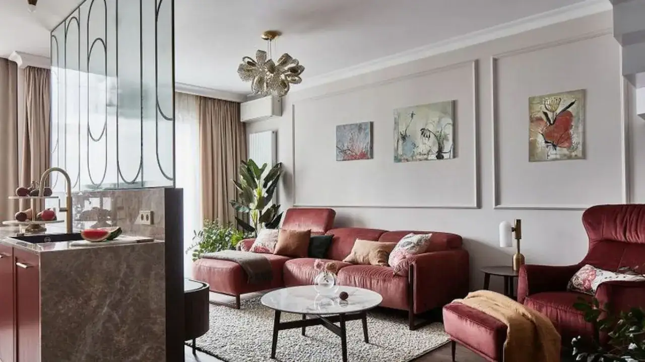 Nowoczesny salon z bordową kanapą i fotelami. Obrazy na ścianie dodają koloru, pokazując, jak udekorować ścianę.