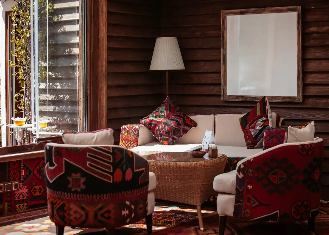Przytulny salon w stylu marokańskim, z sofą, fotelami i dywanami ozdobionymi etnicznymi wzorami.