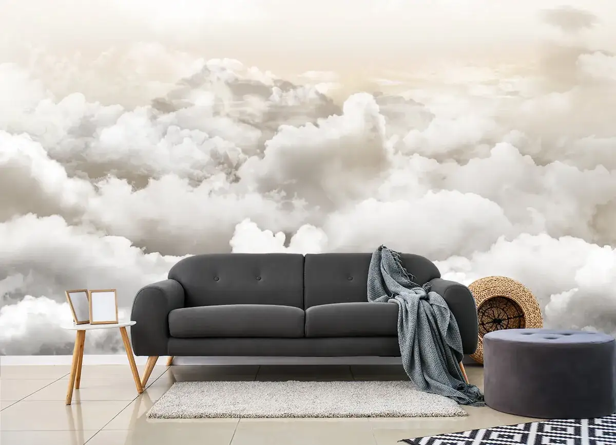 Inspiracja, jak namalować chmury na ścianie: przytulna szara sofa na tle nieba pełnego puchatych obłoków.