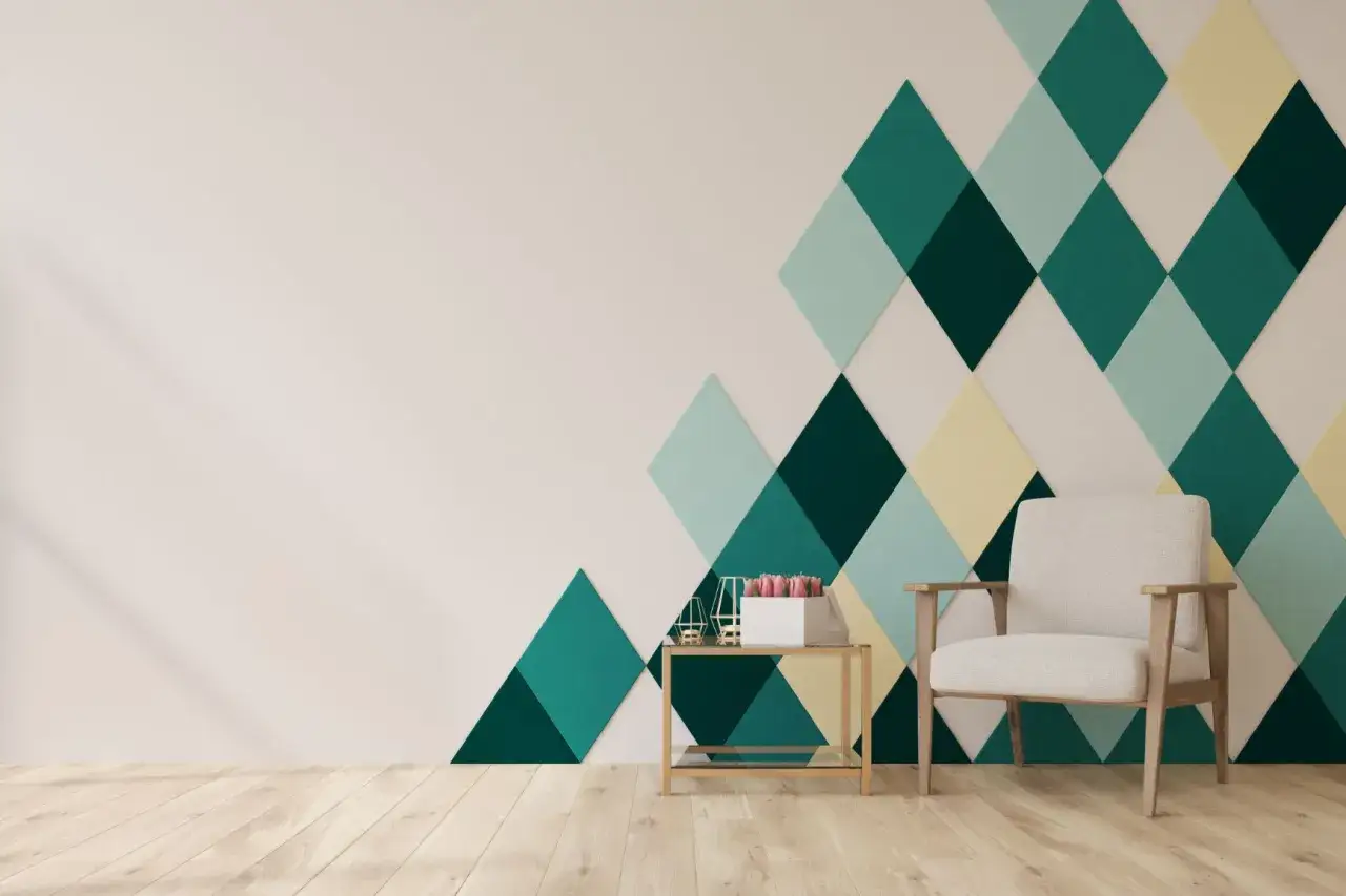 Nowoczesne wnętrze z geometrycznymi wzorami na ścianie z taśmy w odcieniach zieleni i żółci. Wygodny fotel i stolik dodają przytulności.