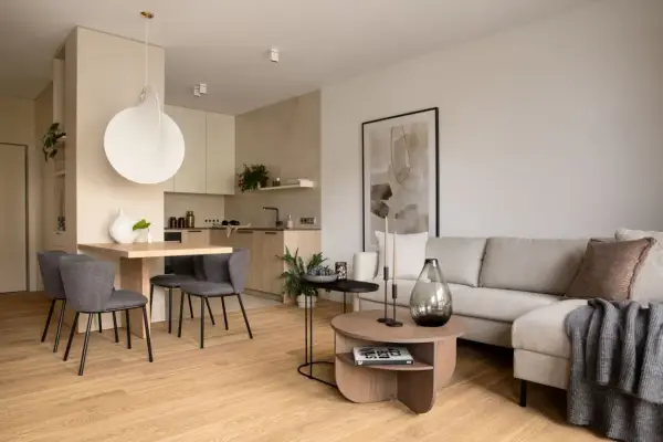 Nowoczesna jadalnia inspiracje: minimalistyczny stół z szarymi krzesłami, obok kuchnia i salon z beżową kanapą.